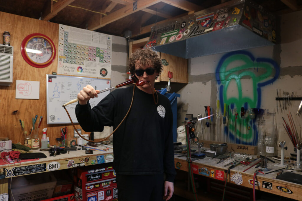 Photo of Wesley Maxwell blowing glass.