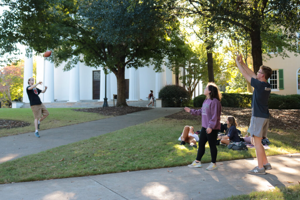 Photo of three students at UGA playing catch with a football