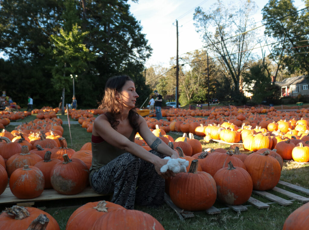 Photo of Emily Hale sitting down in a field of pumpkins.