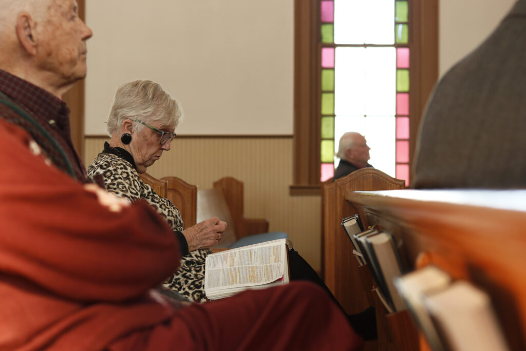 Photo of Sonja Armour reading the bible, sitting in Church